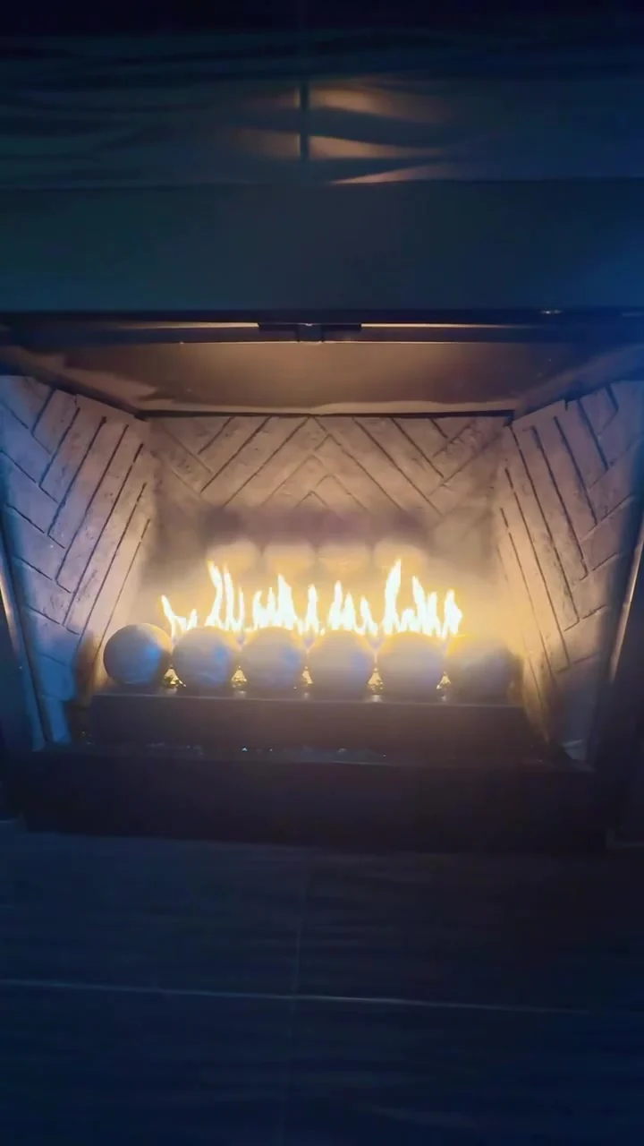 Lit fireplace installation with rounded fire glass in a finished hearth — mobile service overview